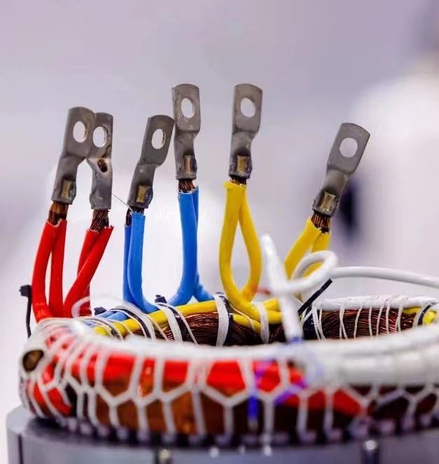EV drive motor stator with three-phase lead wires terminated by ring lugs and laced with white fiberglass sleeving