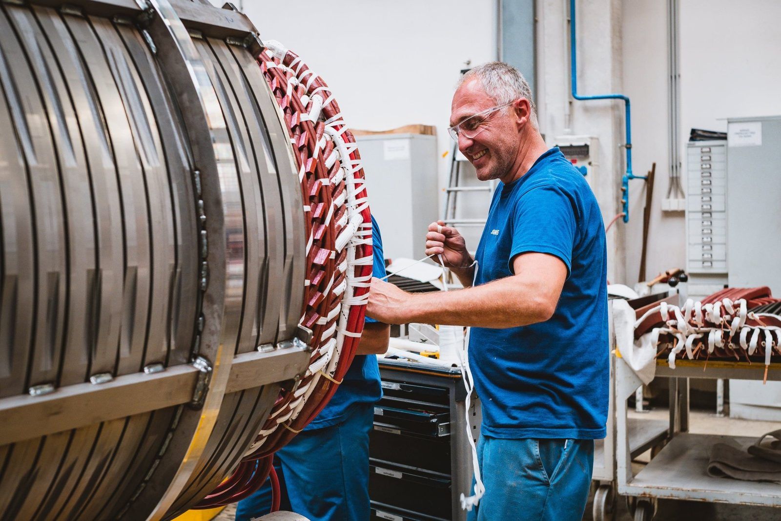Worker insulating the winding of a large generator stator with fiberglass sleeving